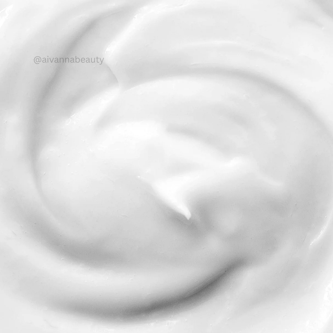 A close-up texture shot of a thick, creamy white lotion or soap, swirled in a smooth spiral pattern.