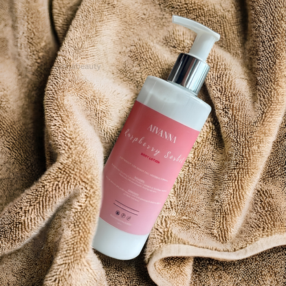 A bottle of ANANNI Raspberry Berry body lotion with a pink label and white pump, resting on a textured beige towel.